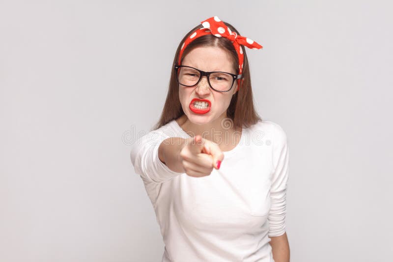Problem beause you are. anger pointing bossy portrait of beautiful emotional young woman in white t-shirt with freckles, glasses, red lips and head band. indoor, isolated on light gray background. Problem beause you are. anger pointing bossy portrait of beautiful emotional young woman in white t-shirt with freckles, glasses, red lips and head band. indoor, isolated on light gray background.