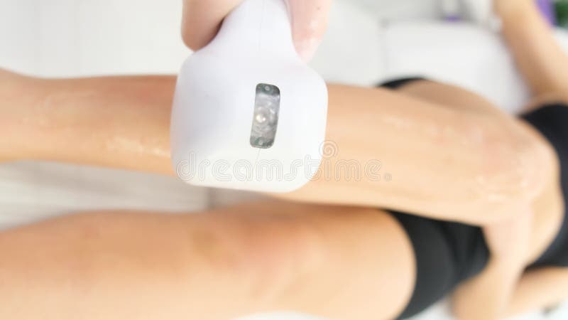 Beautician applying laser hair removal gun on leg of man. Beauty treatment concept.