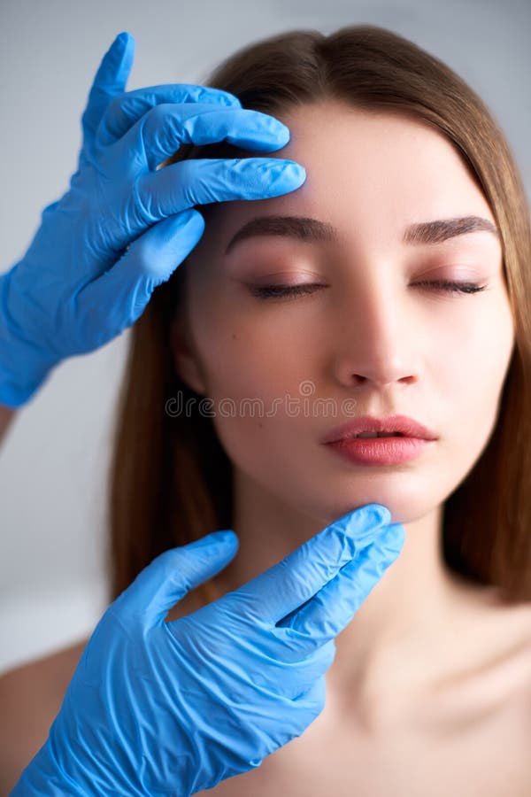 Beautician doctor`s hands in gloves touching face of attractive woman. Fashion blonde model after cosmetic treatment royalty free stock photo Beautician doctor`s hands in gloves touching face of attractive woman. Fashion blonde model after cosmetic treatment royalty free stock photo