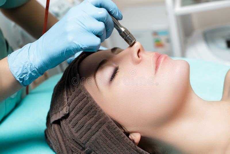 Beautician makes mechanical cleaning of face. Procedure of Microdermabrasion, diamond grinding. royalty free stock photography Beautician makes mechanical cleaning of face. Procedure of Microdermabrasion, diamond grinding. royalty free stock photography