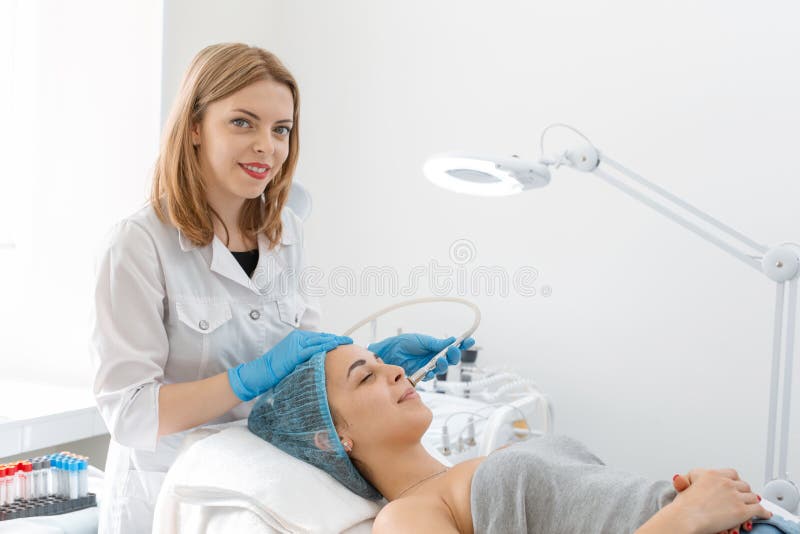 Beautician procedure diamond microdermabrasion patient face. A young girl is undergoing a course of spa treatments in the office