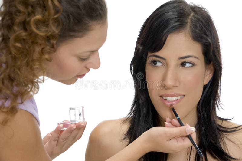 Beautician putting lipstick on female lips