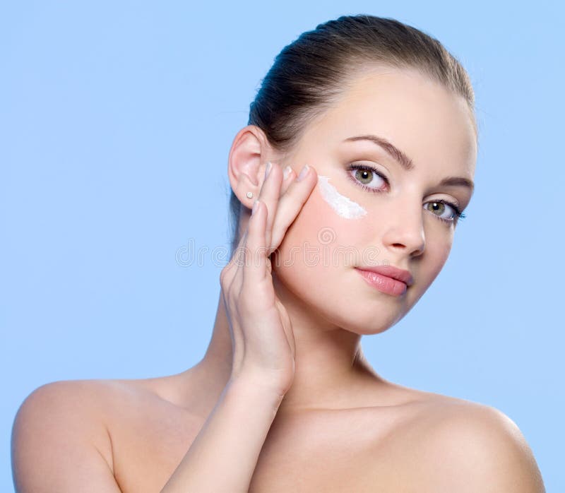 Beautifu woman applying cream on face