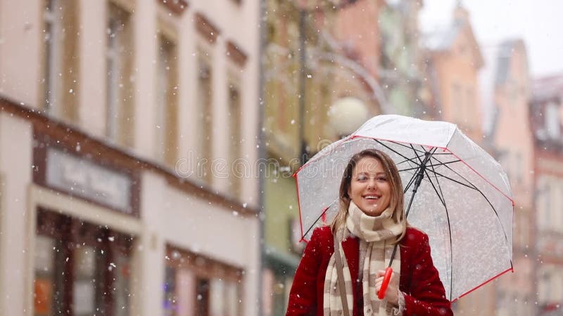 Beautiful adult girl in red coat and scarf with umbrella