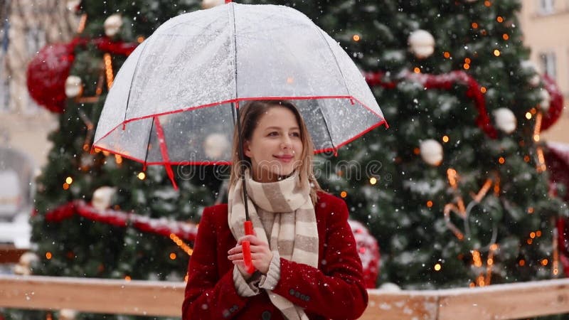 Beautiful adult girl in red coat and scarf with umbrella