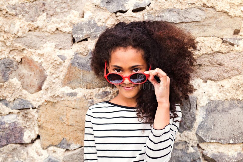 Beautiful african american girl with sunglasses against stone wa