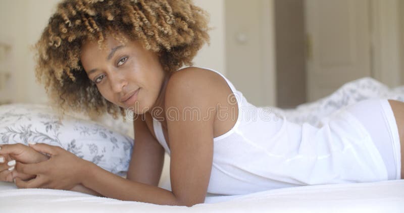 Beautiful african american young woman laying on bed in home