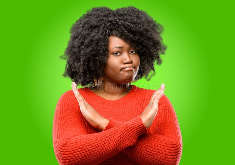 Beautiful african woman with curly hair isolated over green background. Beautiful african woman annoyed with bad attitude making stop sign crossing hands, saying stock images