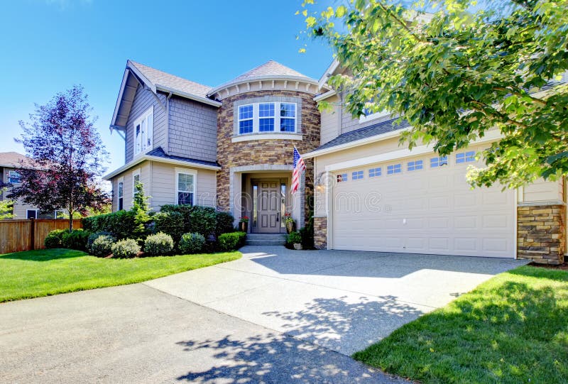 Beautiful American home exterior with stone tower and garage. stock photo