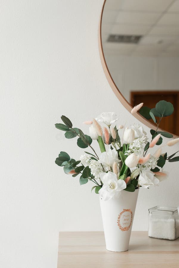 beautiful artificial flowers in a vase on a wall background