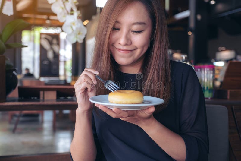 Beautiful Asian Woman Holding A Fork To Cut A Piece Of Donut With Feeling Happy In Cafe Stock 