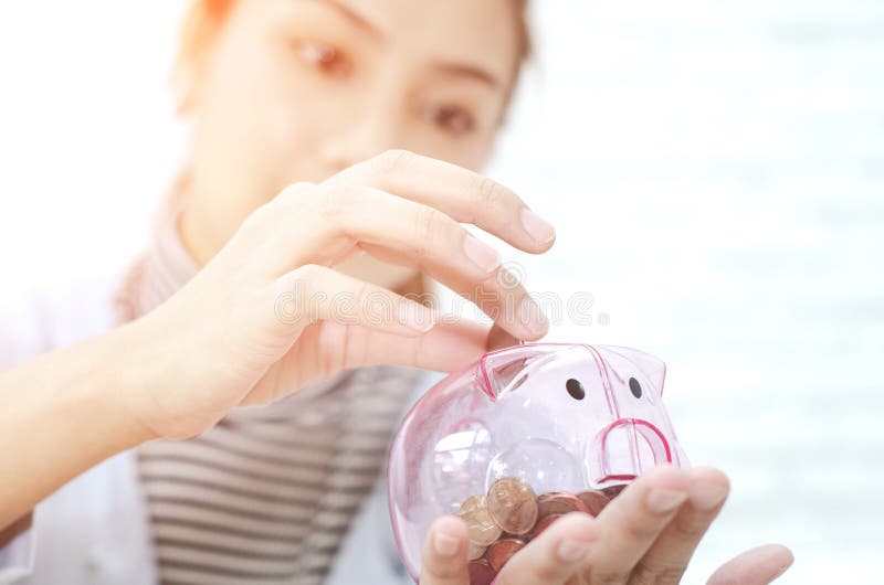 Pink coin jar in Asian women hand.