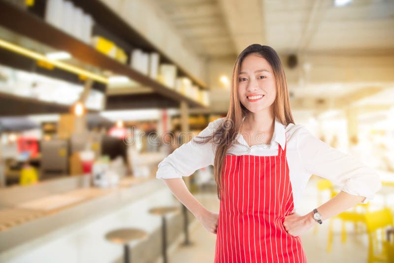 Beautiful asian woman wearing red apron smiling