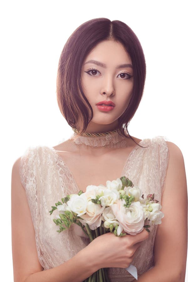Beautiful asian woman in white dress with bouquet of flowers in hands