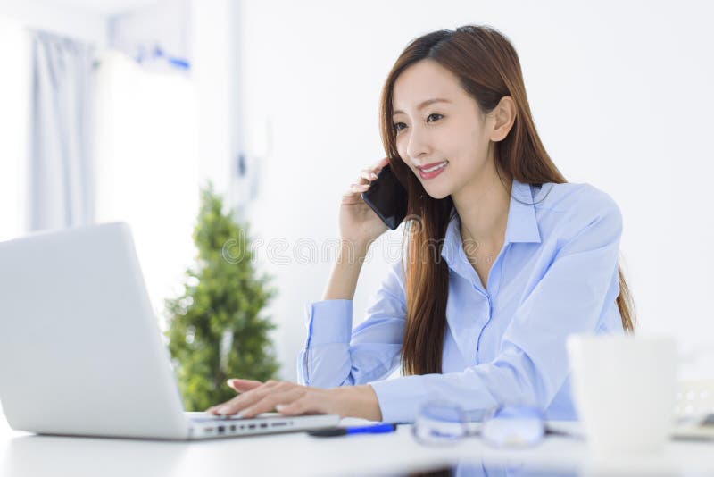 Beautiful Asian young business woman talking on the phone and working in the office