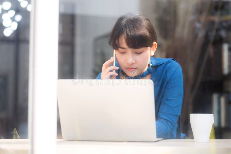 Beautiful asian young businesswoman excited and glad of success work with laptop, girl taking mobile smart phone and working stock photo Beautiful asian young businesswoman excited and glad of success work with laptop, girl taking mobile smart phone and working stock photo