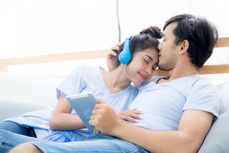 Beautiful asian young couple listening to music with tablet.