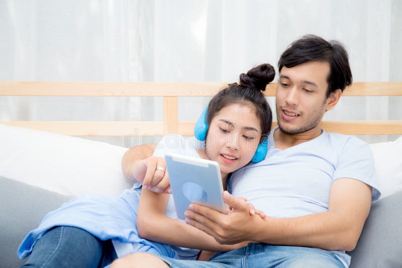 Beautiful asian young couple listening to music with tablet on bed. royalty free stock photography Beautiful asian young couple listening to music with tablet on bed. royalty free stock photography