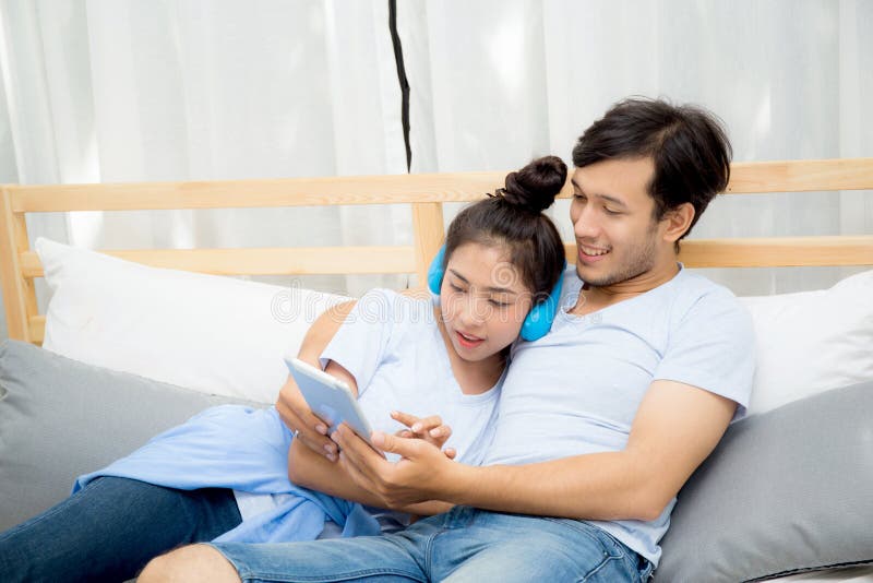 Beautiful asian young couple listening to music with tablet on bed, Love, dating royalty free stock image Beautiful asian young couple listening to music with tablet on bed, Love, dating royalty free stock image