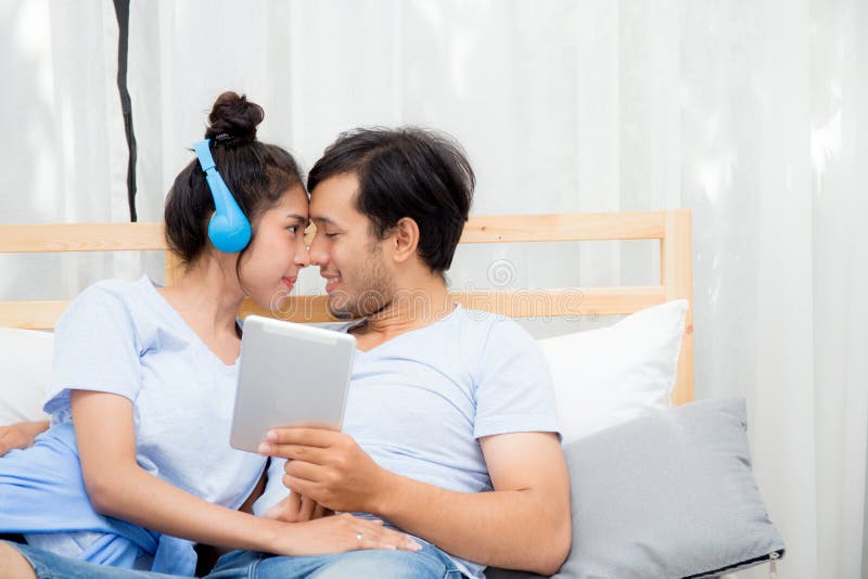 Beautiful asian young couple listening to music with tablet on bed, Love, dating royalty free stock photography Beautiful asian young couple listening to music with tablet on bed, Love, dating royalty free stock photography