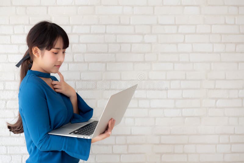 Beautiful asian young woman hipster using working laptop thinking idea on cement concrete background