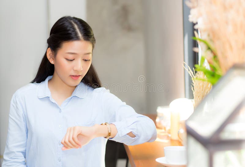 Beautiful asian young woman look at watch waiting for friend or someone.