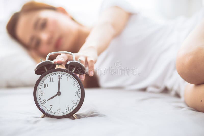 Beautiful asian young woman turn off alarm clock in good morning, wake up for sleep with closeup foreground alarm clock royalty free stock photos Beautiful asian young woman turn off alarm clock in good morning, wake up for sleep with closeup foreground alarm clock royalty free stock photos