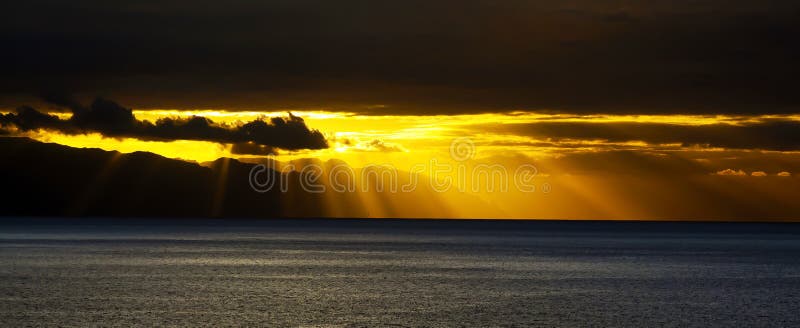 Beautiful atmospheric sky, yellow orange sunset over calm atlantic ocean sea, sun breaking through stratocumulus storm clouds
