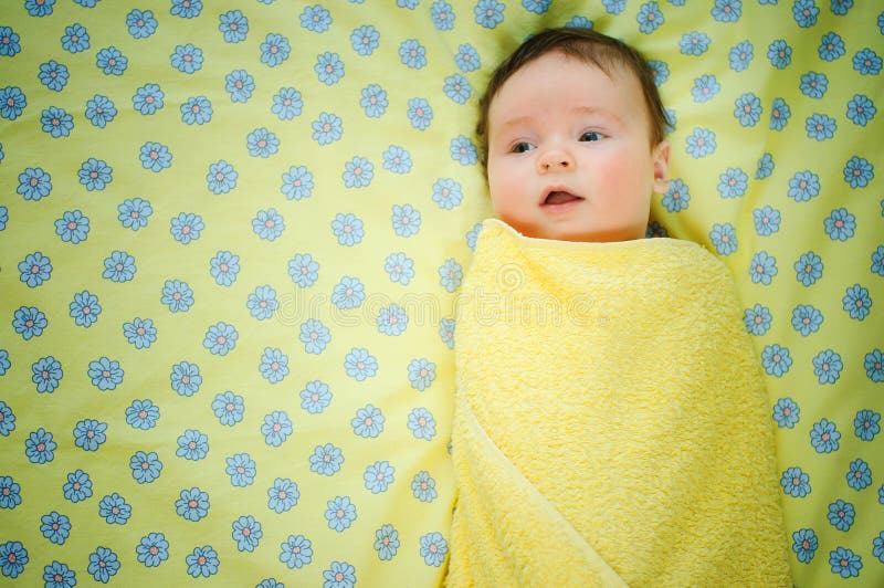 Beautiful baby boy is lying in a bed.