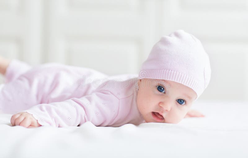 Beautiful baby girl with big blue eyes in pink kni