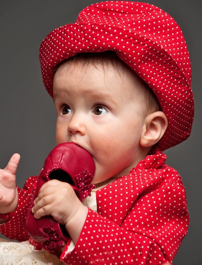Beautiful baby girl dressed in a red dress eating