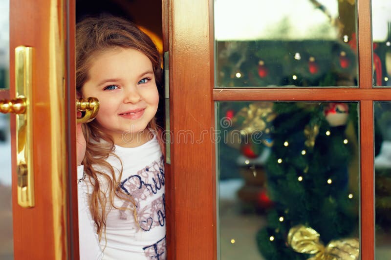 Beautiful baby girl looking out from door