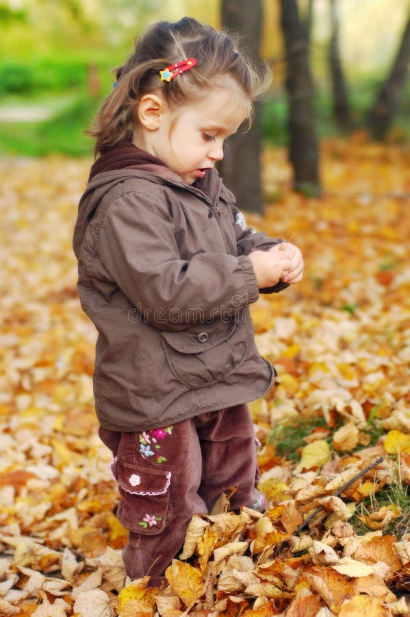 Beautiful baby girl walks in autumn forest