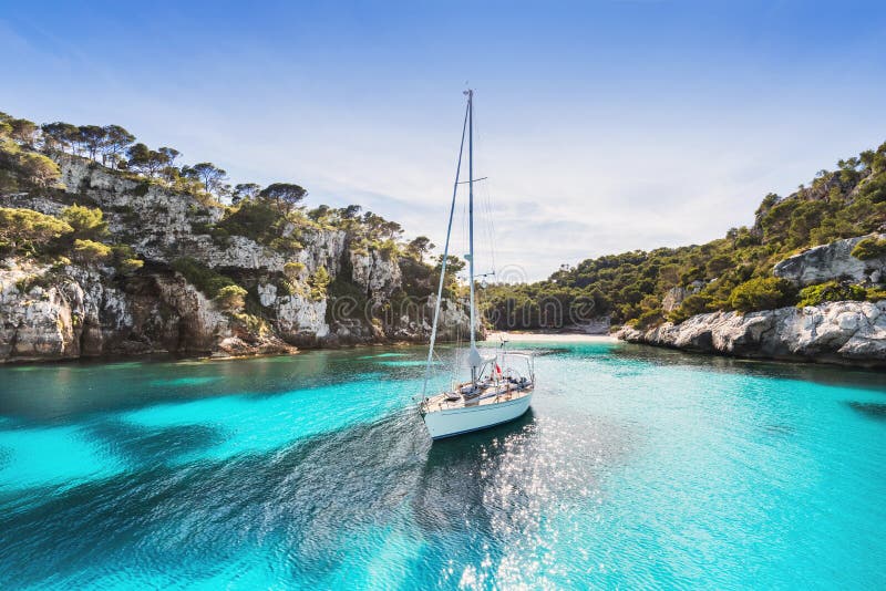 Beautiful beach with sailing boat yacht, Cala Macarelleta, Menorca island, Spain. Yachting, travel and active lifestyle concept