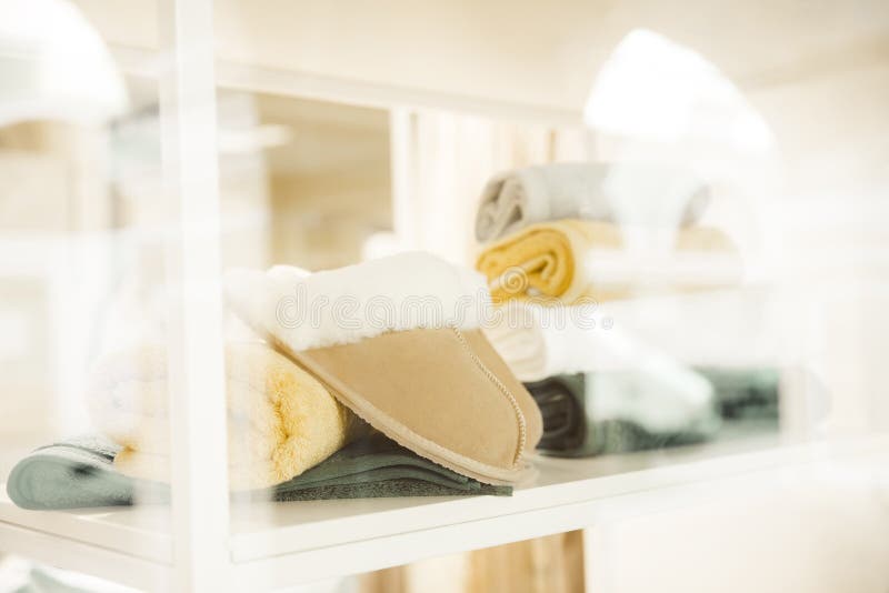 Beautiful beige leather Slippers and green towels on a white shelf. The concept of home comfort, textile shops and spas and good.