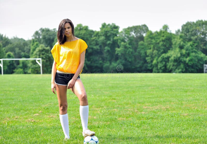 Stunning young biracial (African American and Caucasian) woman soccer player smiling in yellow mesh practice jersey (bib). Stunning young biracial (African American and Caucasian) woman soccer player smiling in yellow mesh practice jersey (bib)