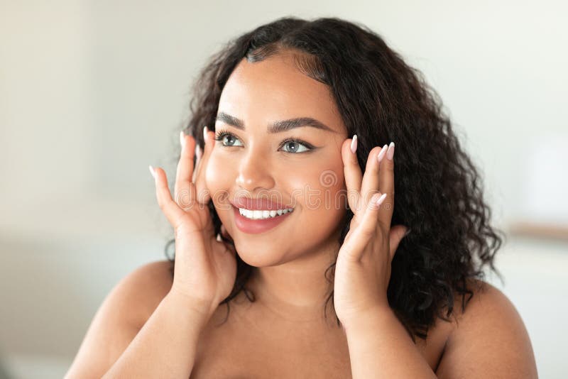 Happy African American Plus Size Woman Smiling At Camera And Touching Her Nose Applying Facial