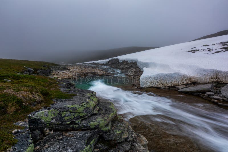 Beautiful bleak summer landscape of tundra with the river and snow in foggy morning royalty free stock photography Beautiful bleak summer landscape of tundra with the river and snow in foggy morning royalty free stock photography