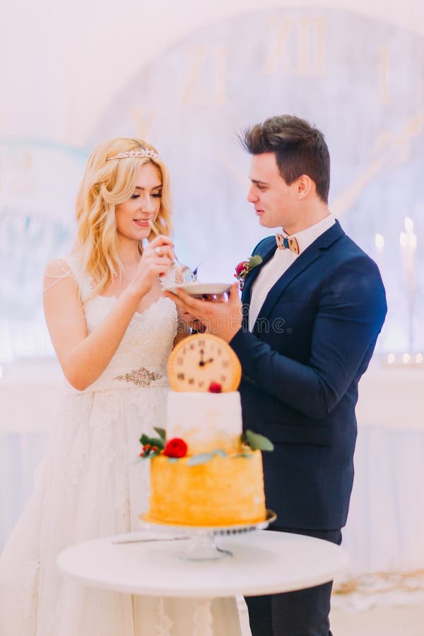 Beautiful blond bride and groom eat the wedding cake together stock photography Beautiful blond bride and groom eat the wedding cake together stock photography