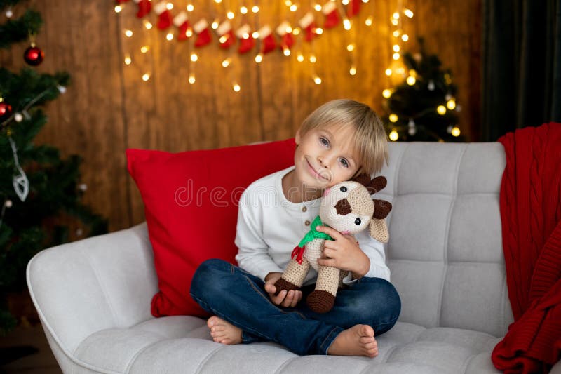 Beautiful blond child, young school boy, playing in a decorated home with knitted toys