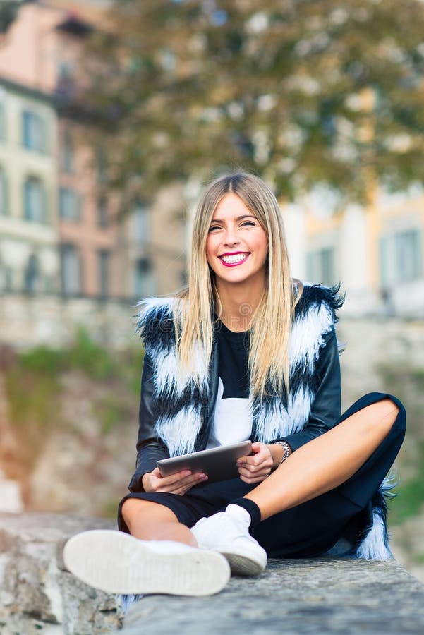 Beautiful blond girl with a big big smile and tablet in hand. Beautiful blond girl with a big big smile and the tablet in hand in the city stock photos Beautiful blond girl with a big big smile and tablet in hand. Beautiful blond girl with a big big smile and the tablet in hand in the city stock photos