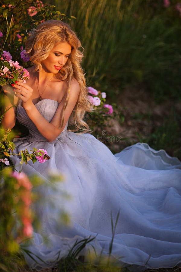 Beautiful blond girl in elegant dress posing in summer