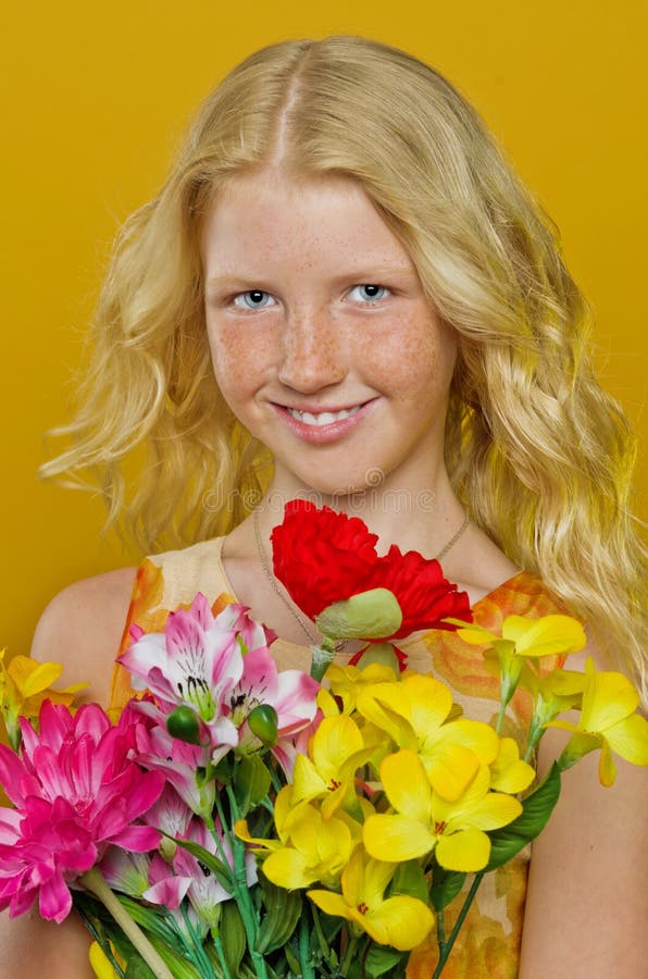 Beautiful blond girl with freckles holding a bouquet of flowers