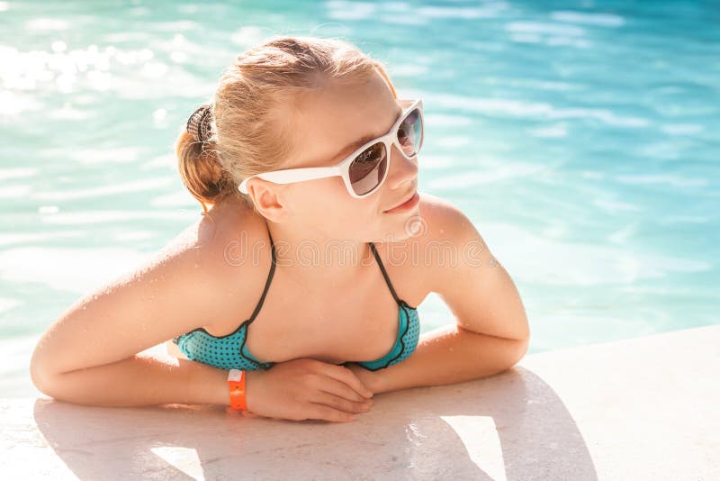 Beautiful blond girl with sunglasses in outdoor pool