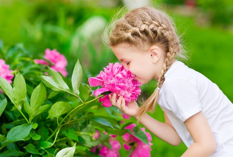 Beautiful blond little girl with long hair smelling flower stock photos