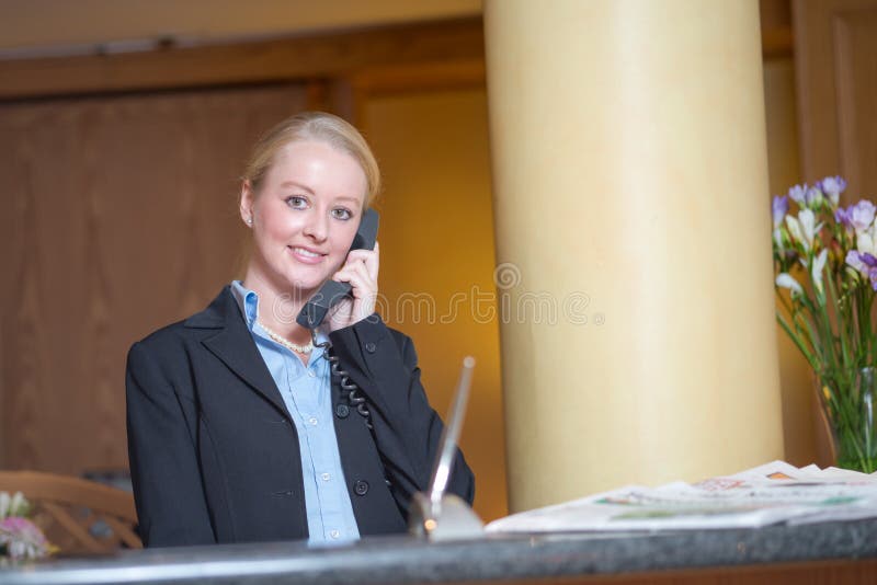 Beautiful blond woman wearing a suit answering an office telephone at work. Beautiful blond woman wearing a suit answering an office telephone at work