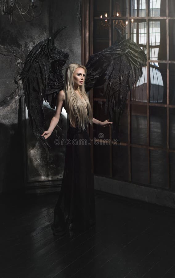 Beautiful blond woman in black dress with black wings stock photography