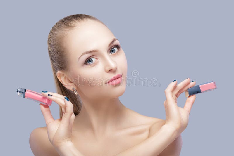 Beautiful blond woman holding pink lip gloss on gray background. lip makeup royalty free stock photo Beautiful blond woman holding pink lip gloss on gray background. lip makeup royalty free stock photo
