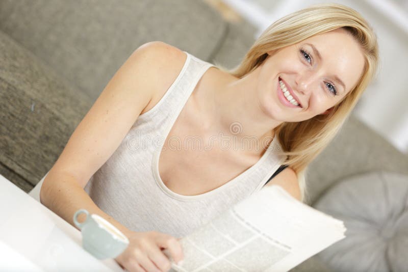 Beautiful blond woman reading news paper while drinking coffee