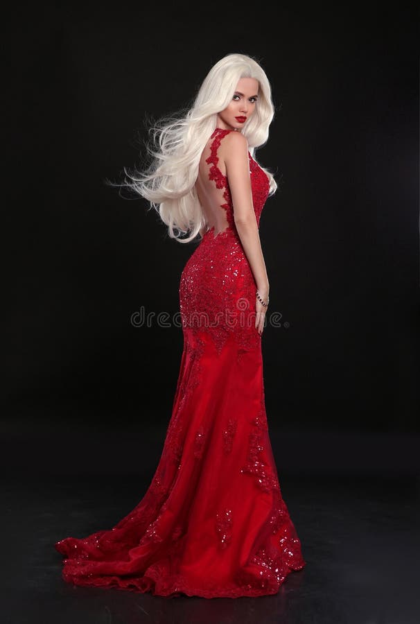 Beautiful blond woman in red dress isolated on black background.